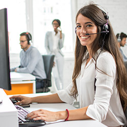 Friendly customer support service operator with headset working in call centre.